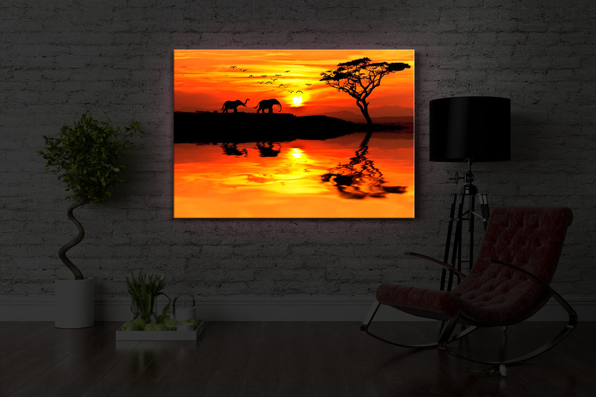 leuchtbild mit dem Motiv Elefanten in afrikanischer Steppe in einem dunklen Raum. Das Bild leuchtet rot im abgedunkelten Zimmer