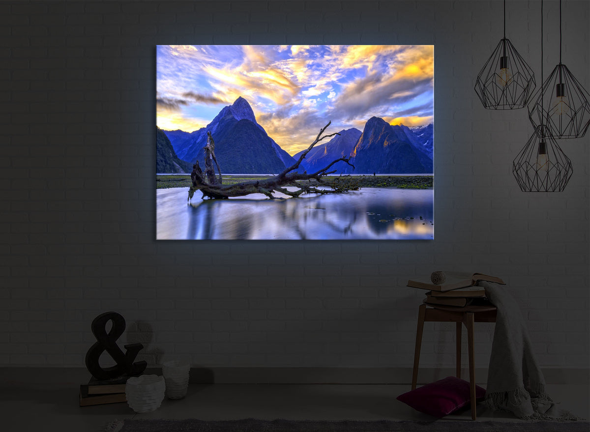 beleuchtetes bild mit dem Motiv Entwurzelter Baum in wunderschöner Berglandschaft in einem dunklen Raum. Das Bild leuchtet blau im abgedunkelten Zimmer