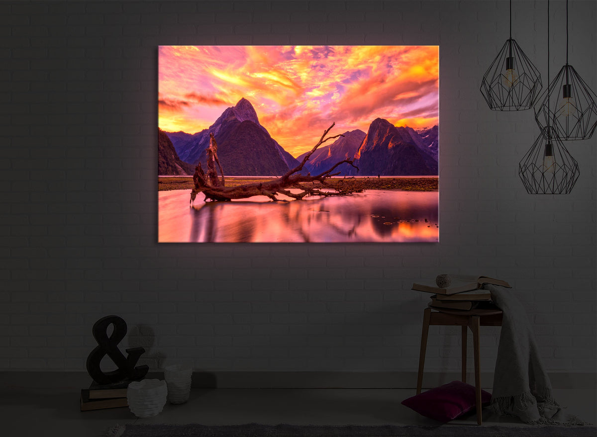 leuchtbild mit dem Motiv Entwurzelter Baum in wunderschöner Berglandschaft in einem dunklen Raum. Das Bild leuchtet rot im abgedunkelten Zimmer