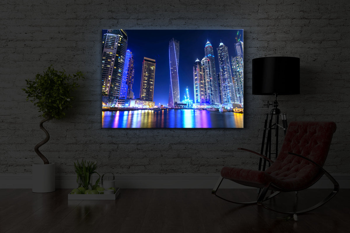 beleuchtetes bild mit dem Motiv Dubai Skyline mit Cayan Tower in einem dunklen Raum. Das Bild leuchtet blau im abgedunkelten Zimmer