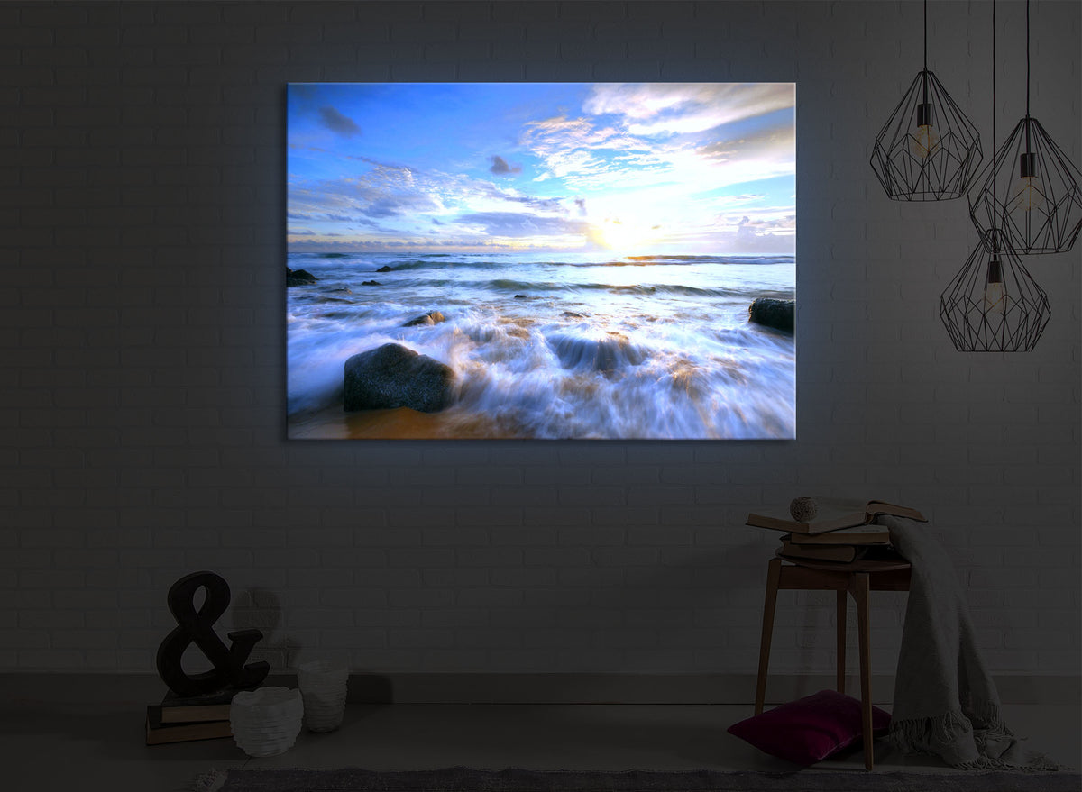 beleuchtetes bild mit dem Motiv Sonnenuntergang am Meer in einem dunklen Raum. Das Bild leuchtet blau im abgedunkelten Zimmer