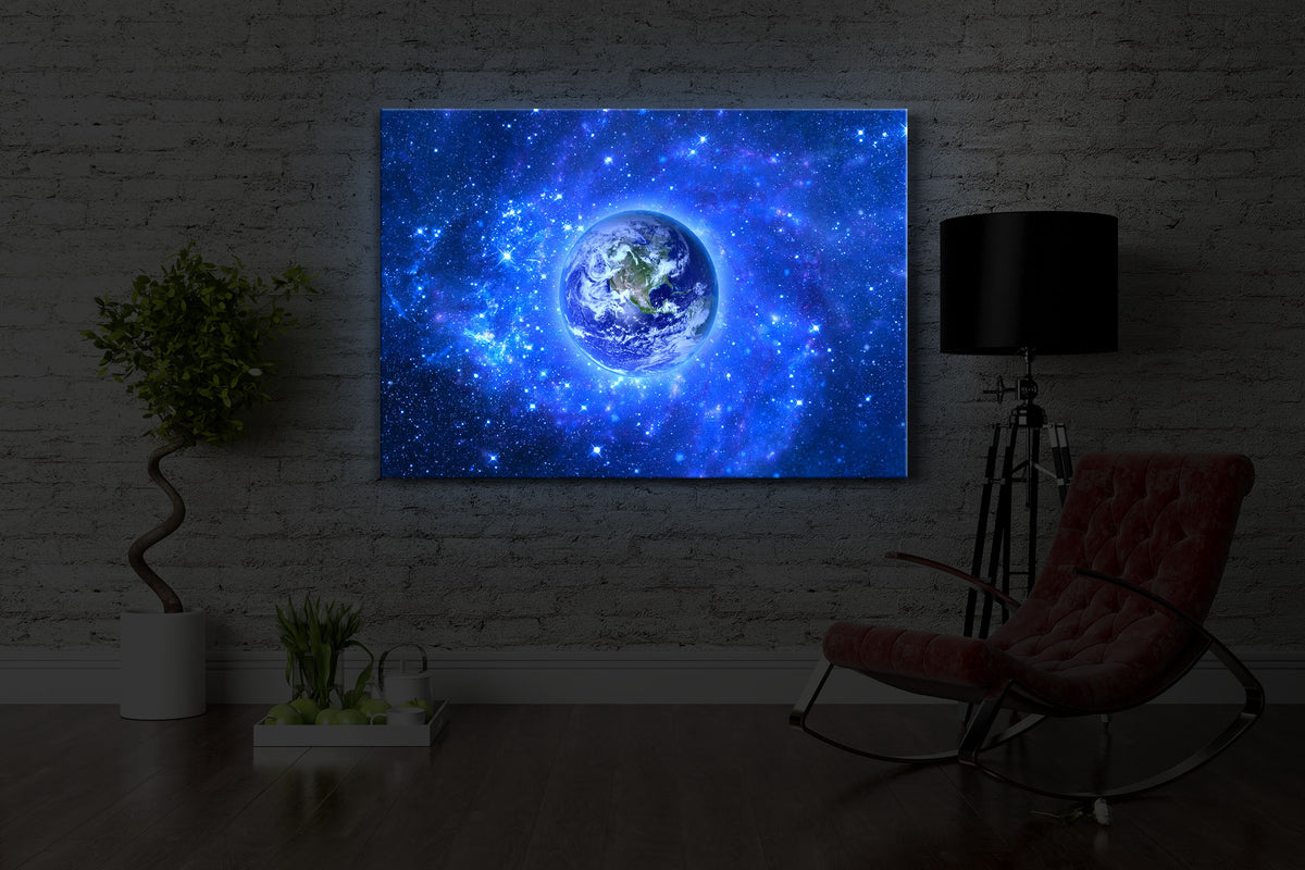 beleuchtetes bild mit dem Motiv Planet Erde im Weltraum in einem dunklen Raum. Das Bild leuchtet blau im abgedunkelten Zimmer